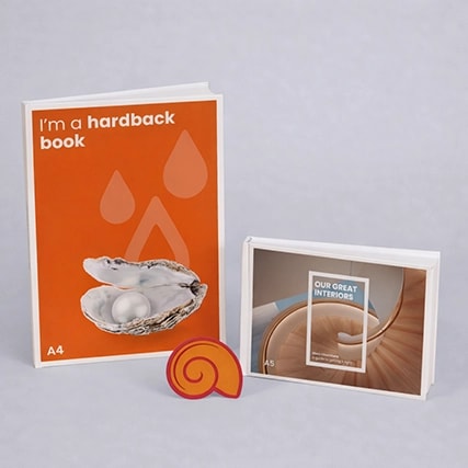 Two books, one with an orange cover and one with a photo cover, next to a shell-shaped object.