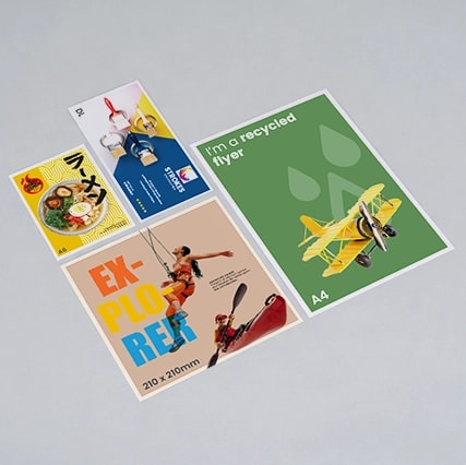 Four printed flyers of various sizes and designs arranged on a light gray surface.