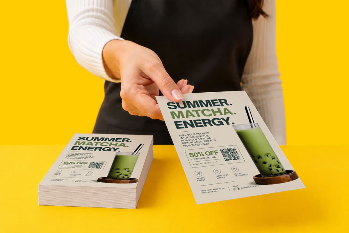 Person holding a flyer advertising a 50% off matcha drink special against a yellow background.