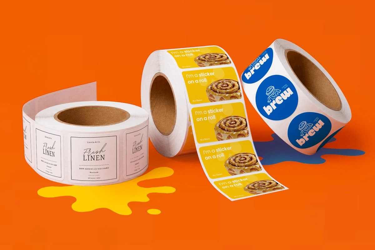 Three rolls of blank adhesive labels on an orange background with yellow and blue paint splats.