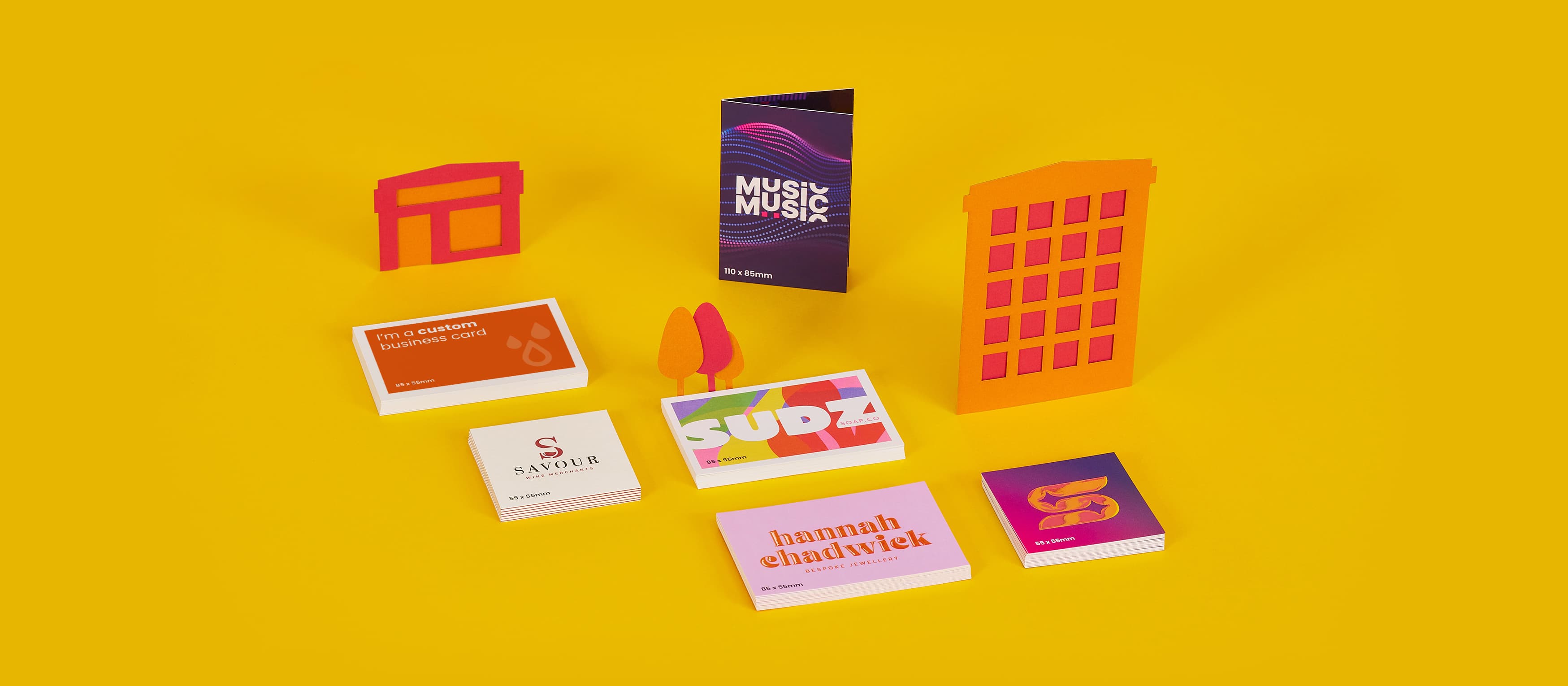 Various colourful business cards displayed with abstract cityscape models on a yellow background.