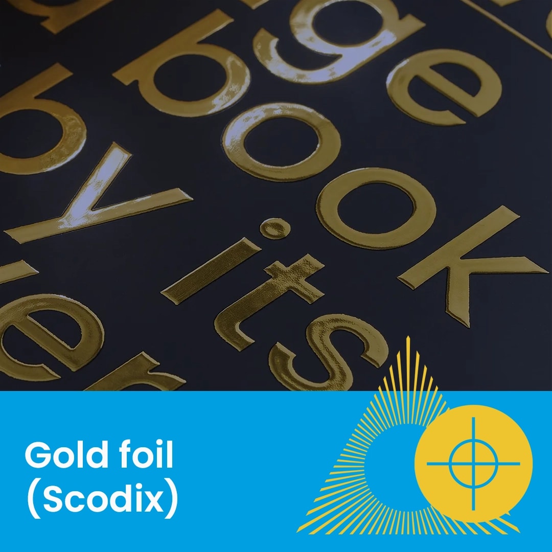 Close-up of gold foil text on a dark surface with a blue label reading "Gold foil (Scodix)".