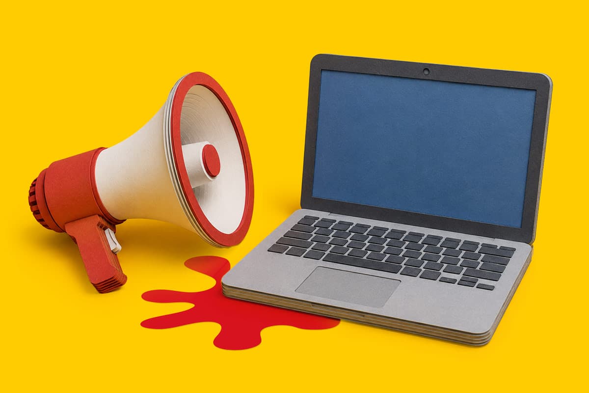 A paper megaphone and laptop with a red spill on a yellow background.