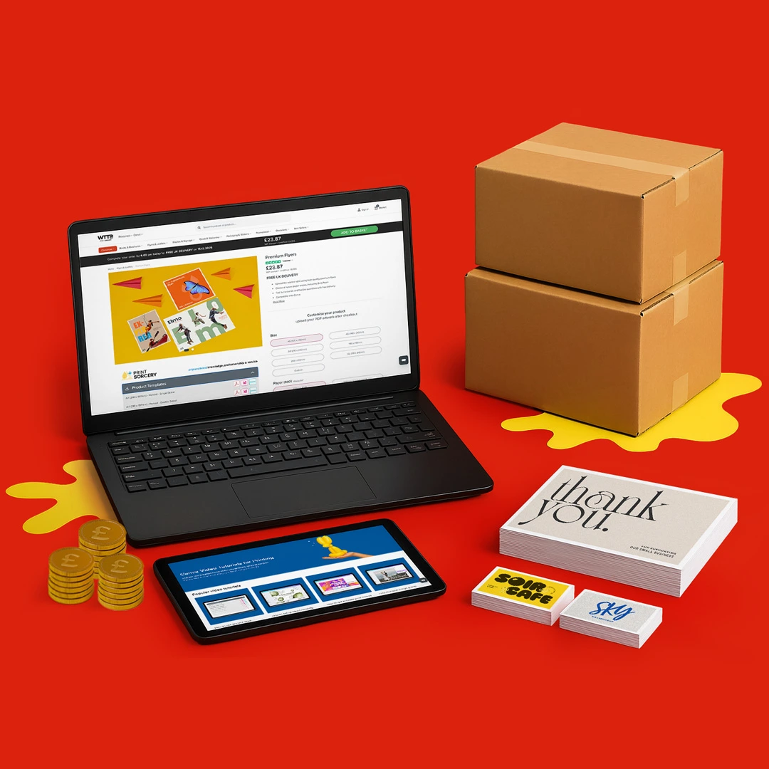 A laptop, tablet, boxes, coins, and printed cards on a red background with yellow accents.