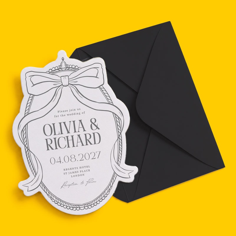 Die cut Wedding invitation card with bow design and black envelope on a yellow background.