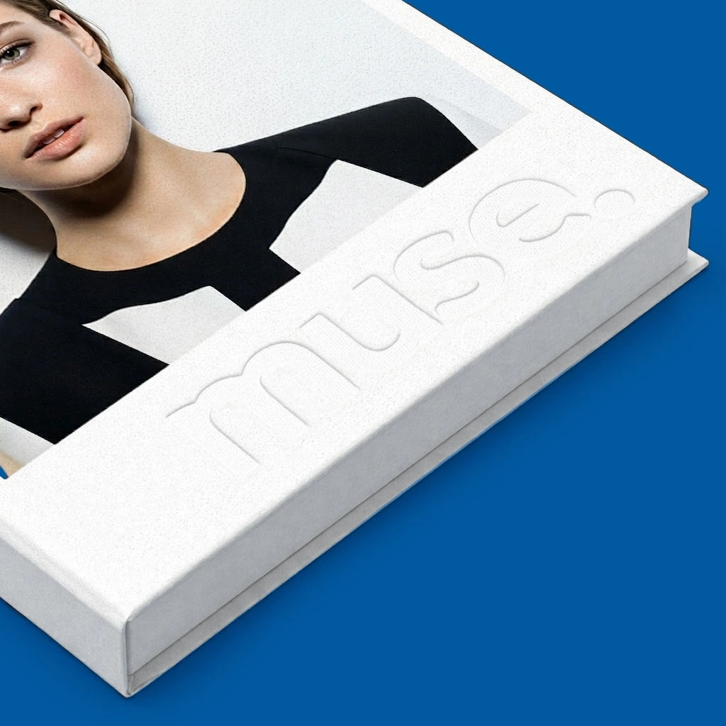 A white book with "muse." embossed on the cover, featuring a woman in black and white attire.